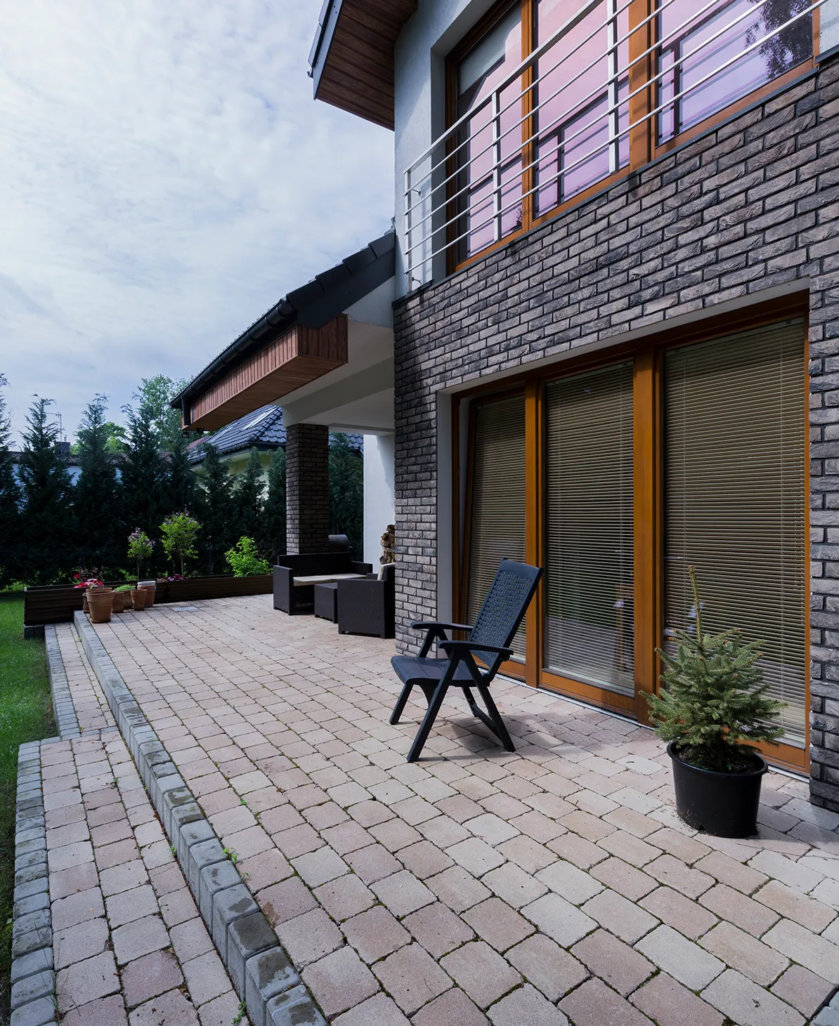 Gepflasterte Terrasse am Einfamilienhaus mit Gartenbereich