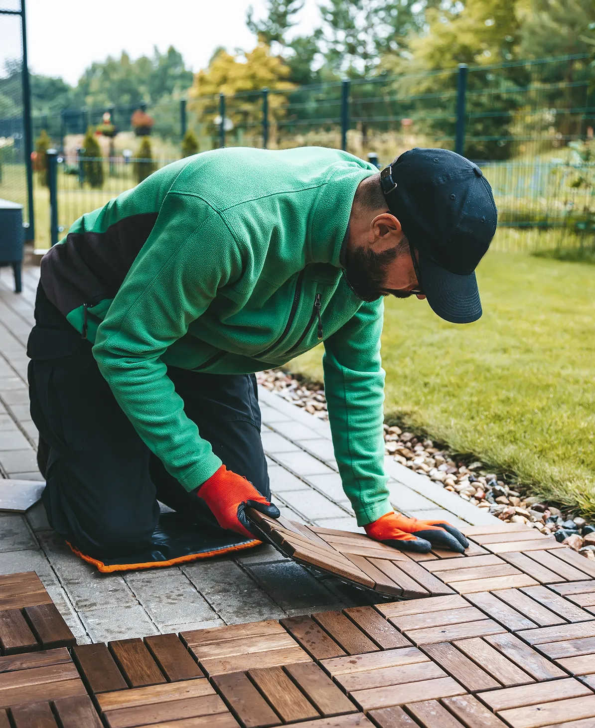 Handwerker verlegt Holzfliesen auf einer Terrasse im Garten